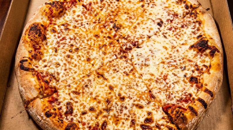 A whole, sliced cheese pizza with a golden-brown crust sits in a cardboard box.
